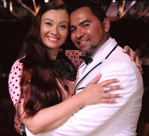 A joyful couple embraces and smiles warmly at a festive event.