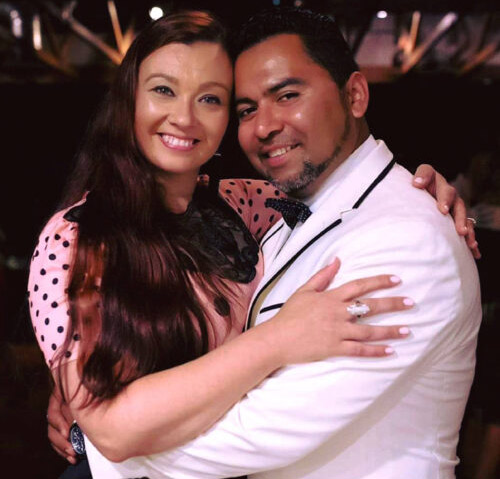 A joyful couple embraces and smiles warmly at a festive event.