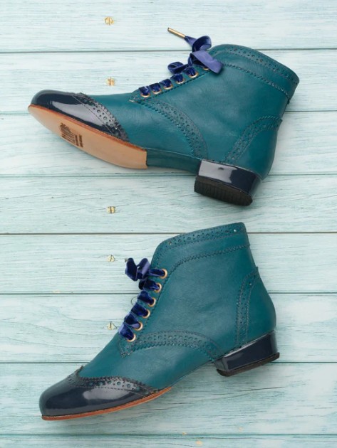 Teal ankle boots with block heels on a wooden floor.