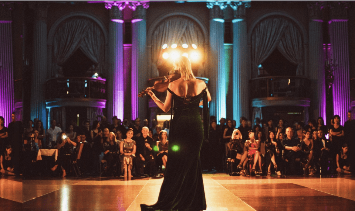 Violinist performing on stage in elegant venue.