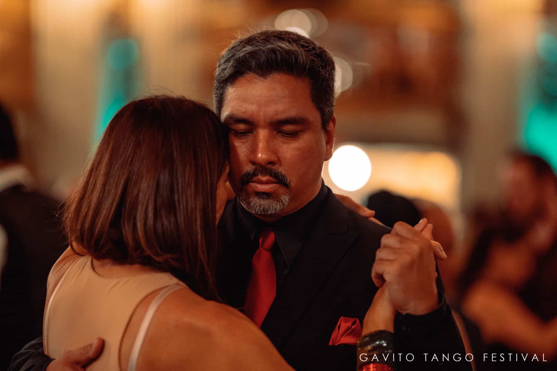 A man and woman share a dance in a warmly lit setting.