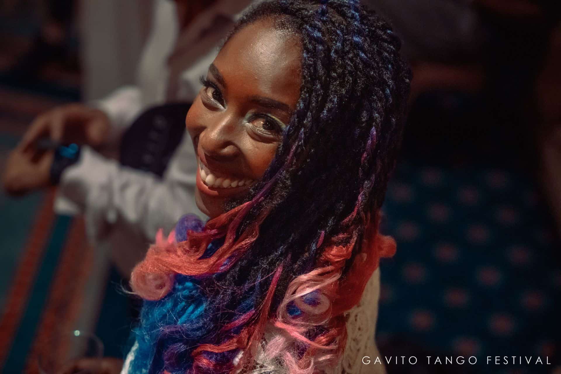 Person dancing joyfully with expressive hand gestures and colorful hair.