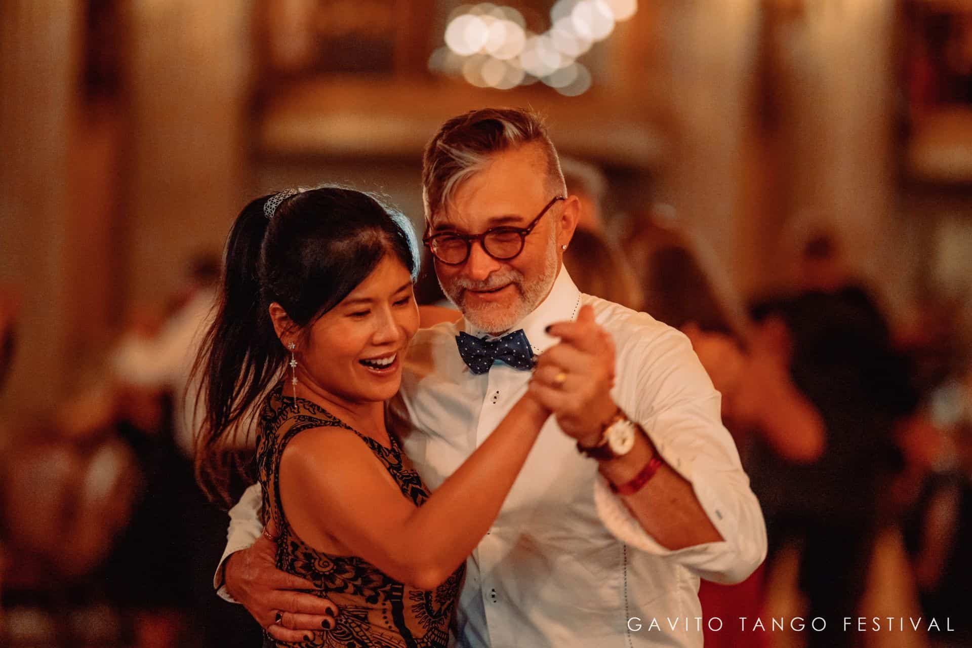 A joyful couple dancing closely at a festive event.