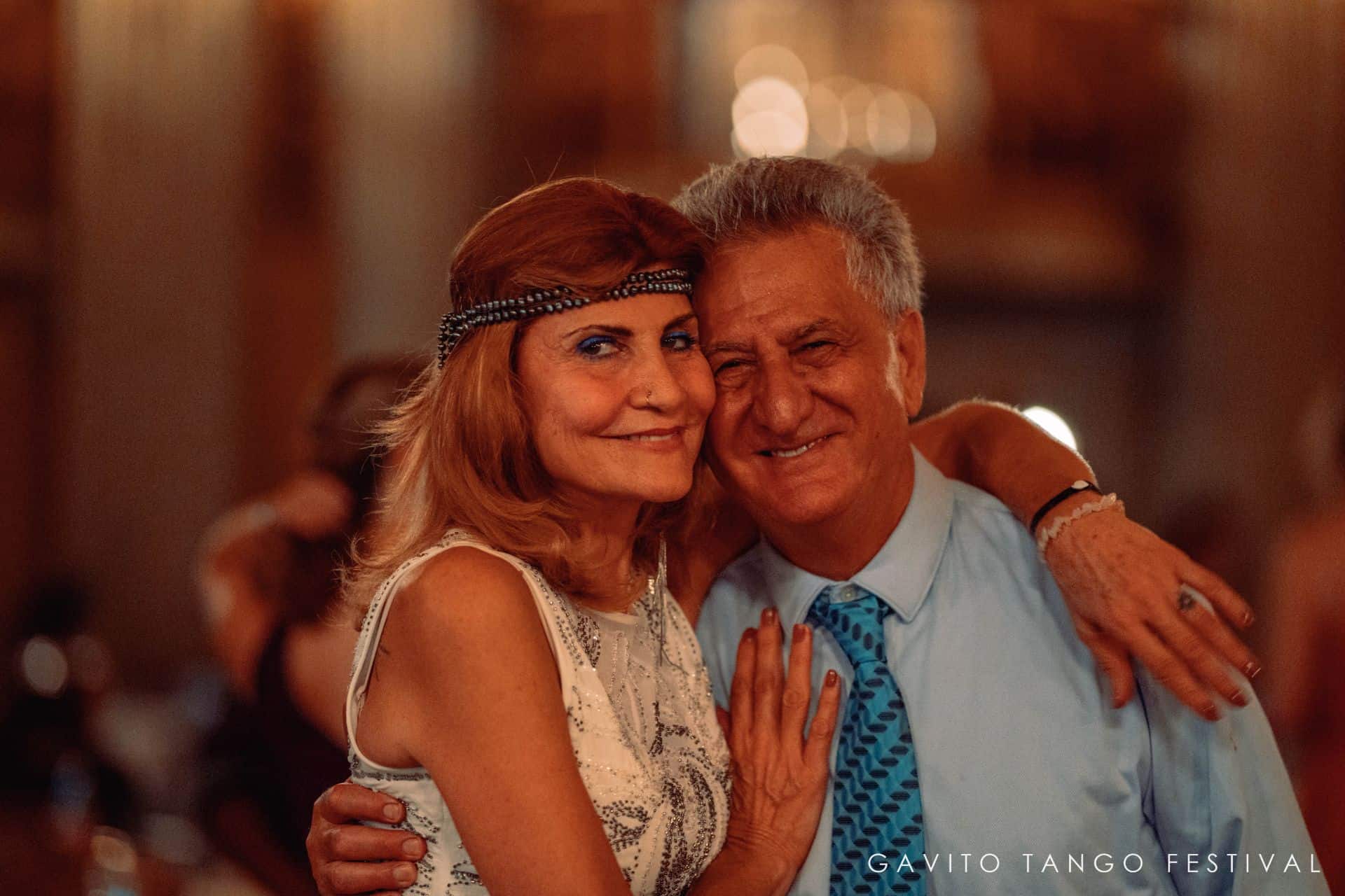 A couple smiling warmly, embracing each other.