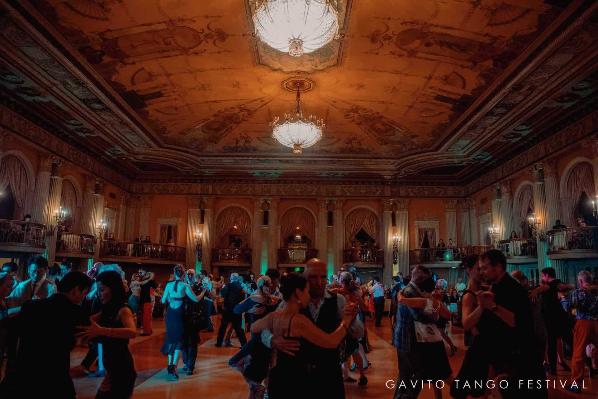 A lively group dance in a warmly lit ballroom with wooden decor.
