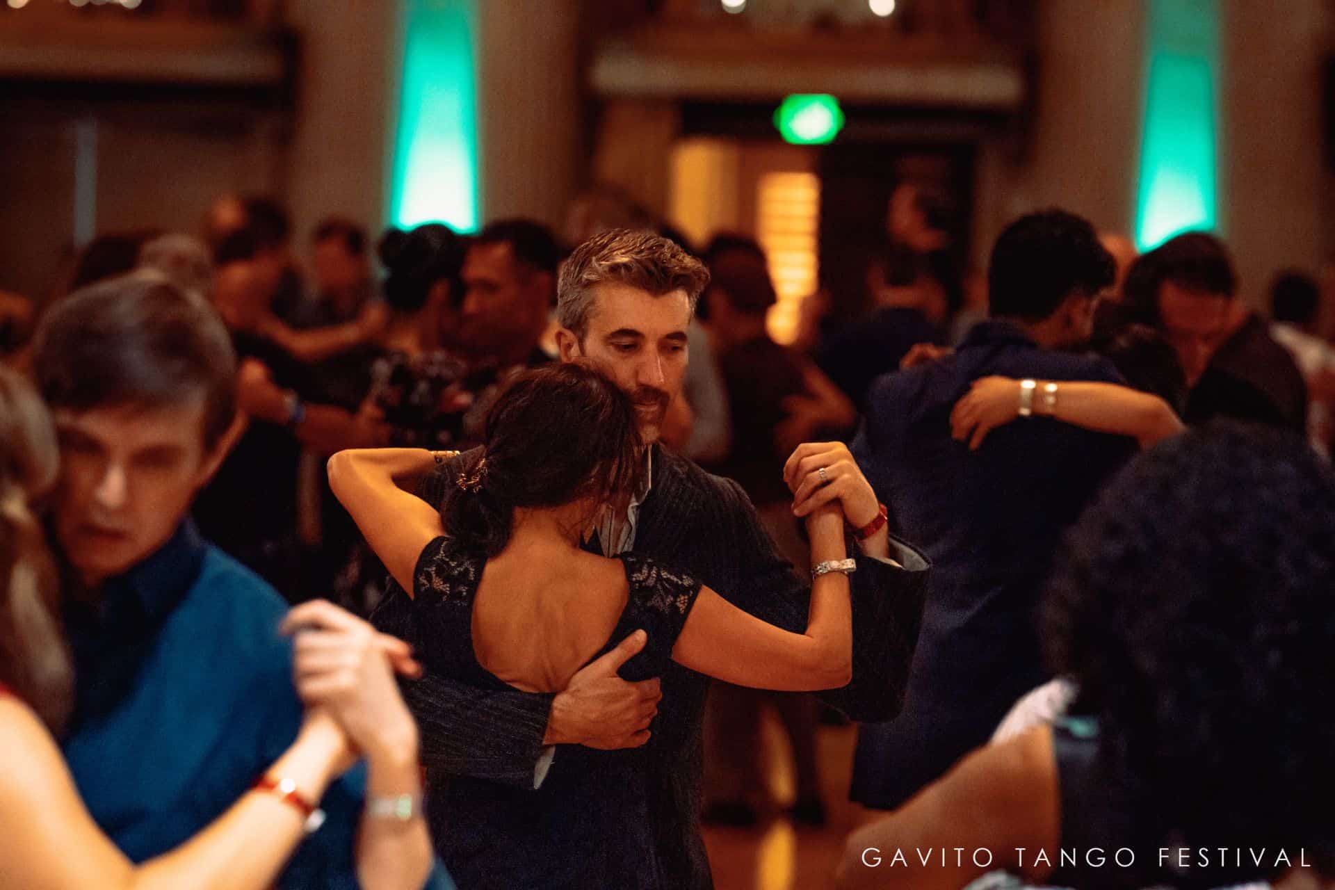 Couple dancing closely in a crowded event.