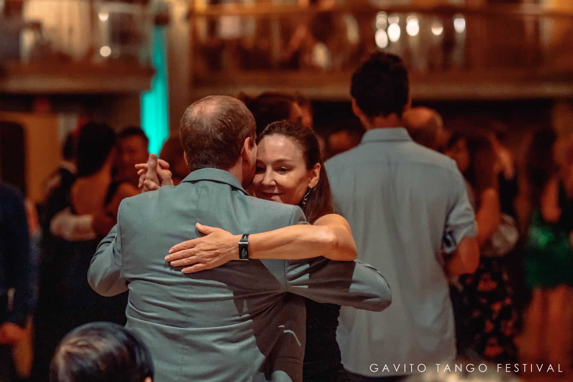 Two people warmly embracing in a crowded indoor setting.