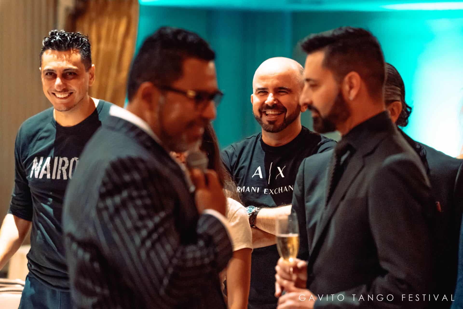 Three men in casual attire enjoying a lively conversation with drinks.