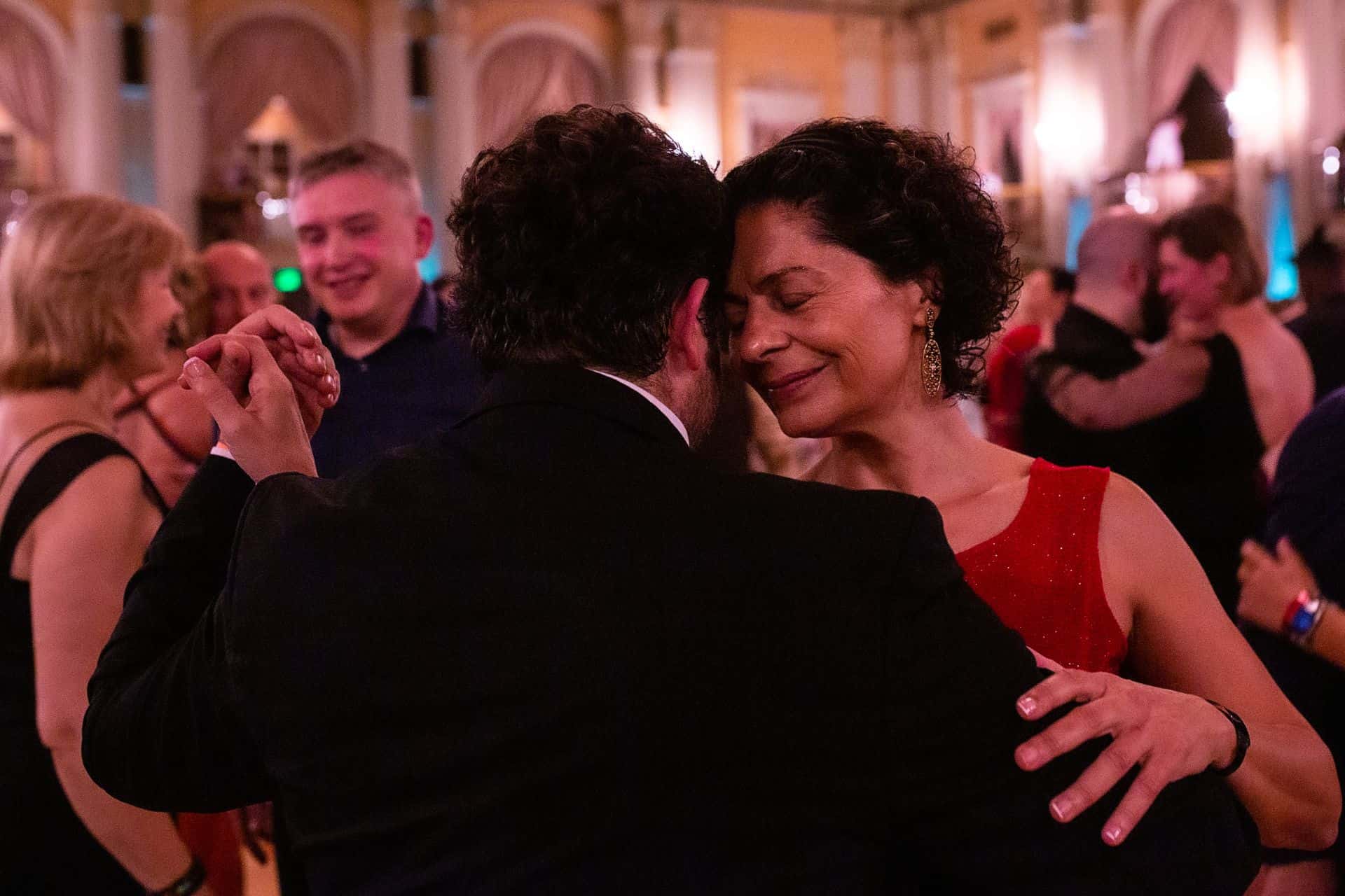 A joyful couple dancing closely at a lively event.