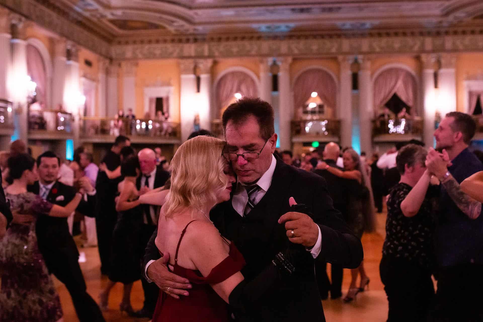 A man holding a baby in a grand ballroom.