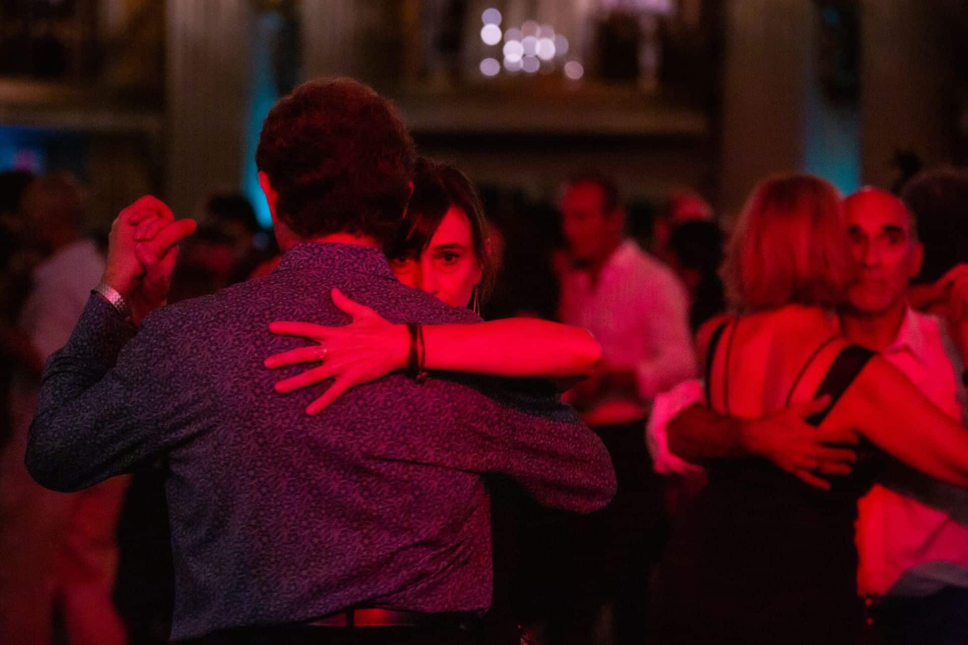 Couple sharing a tender moment in dim red lighting.