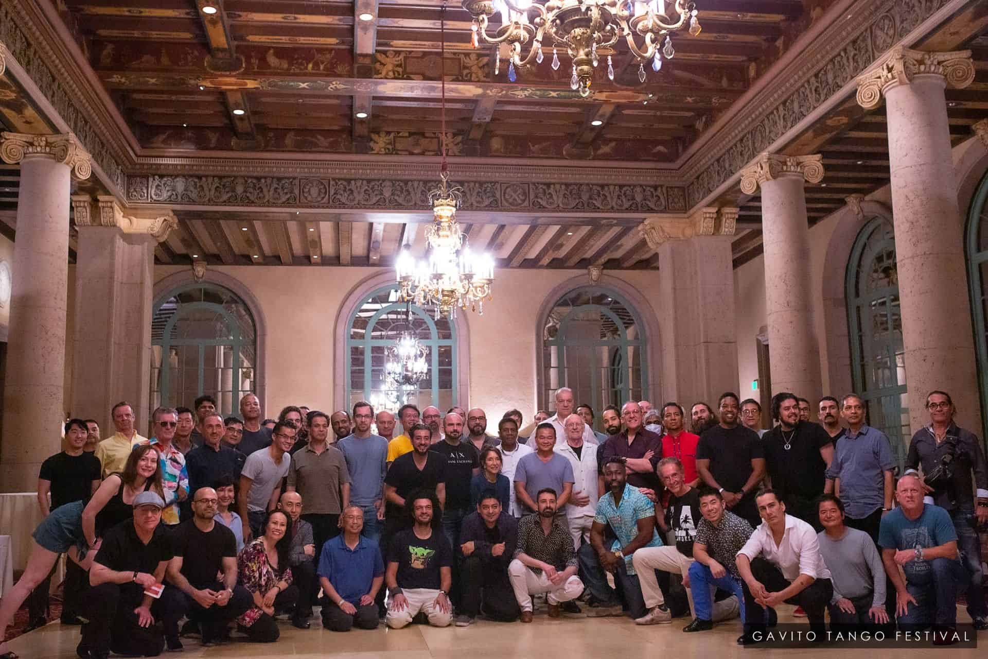 Large group gathered in an ornate hall with chandeliers and elegant decor.