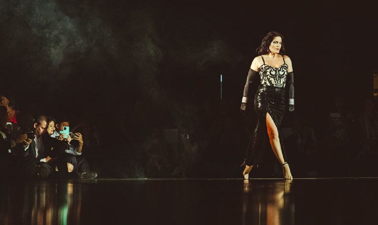 A singer performs on stage with dramatic lighting and smoke effects.