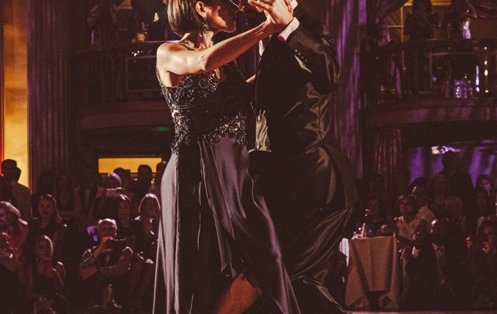 Couple dancing closely in a dimly lit venue with warm lights.