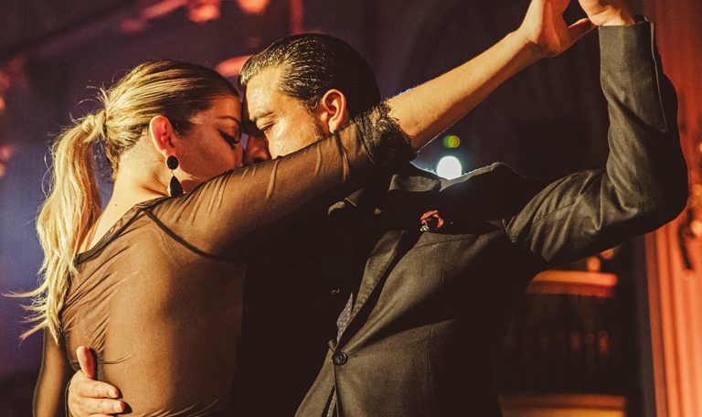 Two men dancing closely under warm, intimate lighting.
