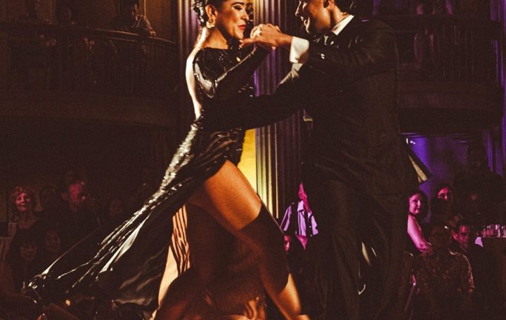 A passionate couple dancing tango on a dimly lit stage.