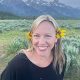 Smiling woman outdoors with a flower in her hair.