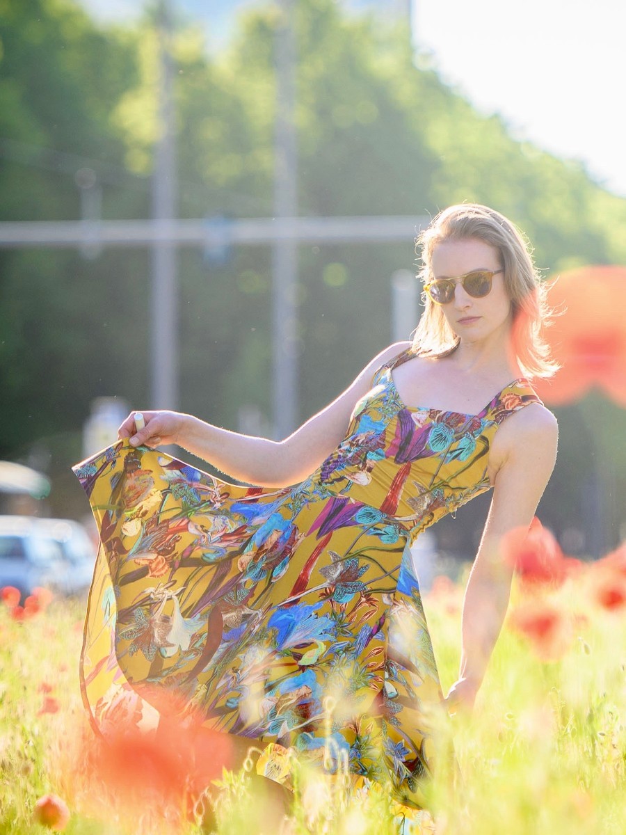 Woman in a vibrant butterfly dress enjoying a sunny garden.
