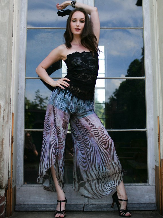 Woman poses in a stylish black top and shimmering pleated skirt.