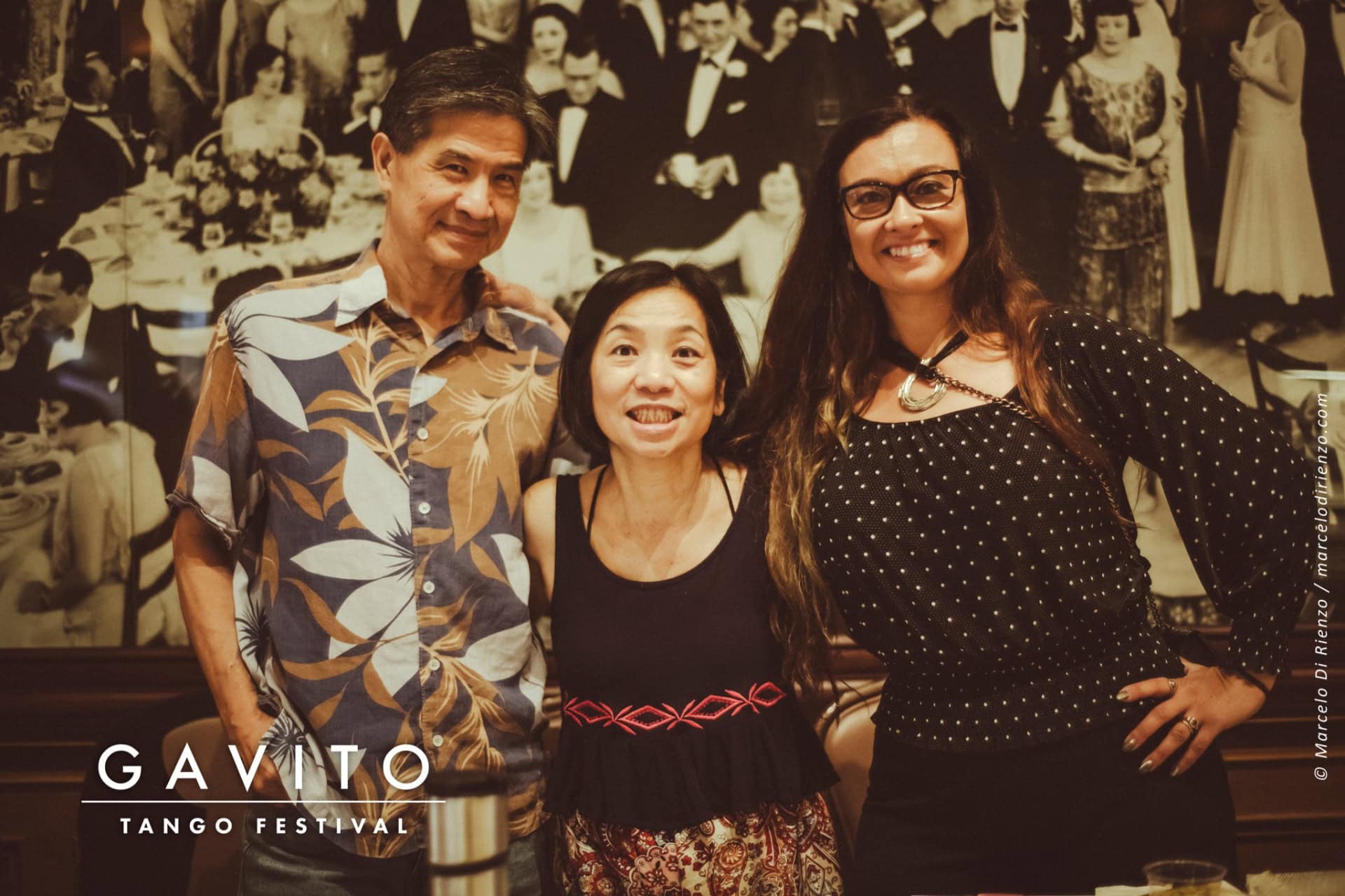 Three people smiling and posing together indoors.