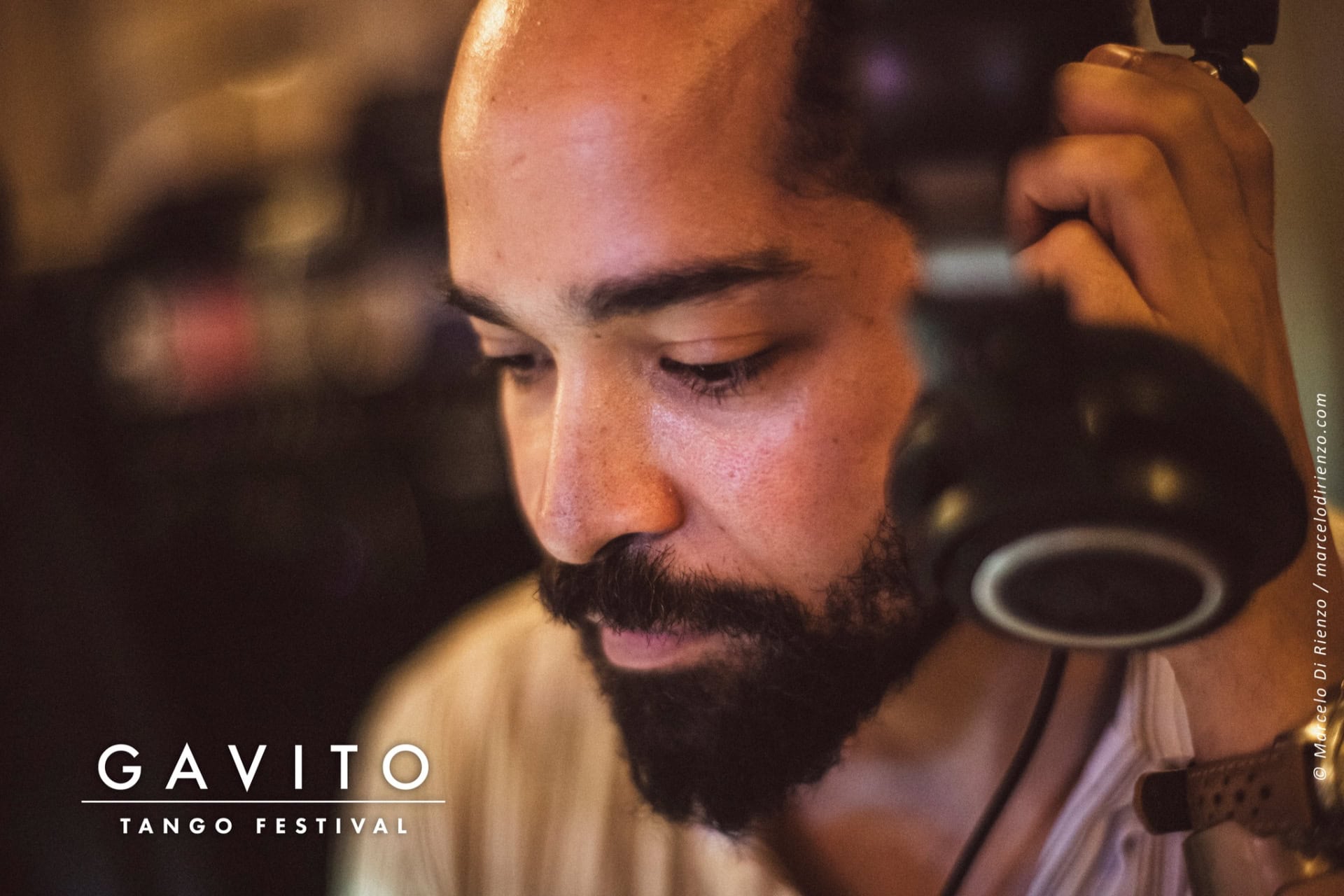 A focused man with a beard and headphones in a dimly lit setting.