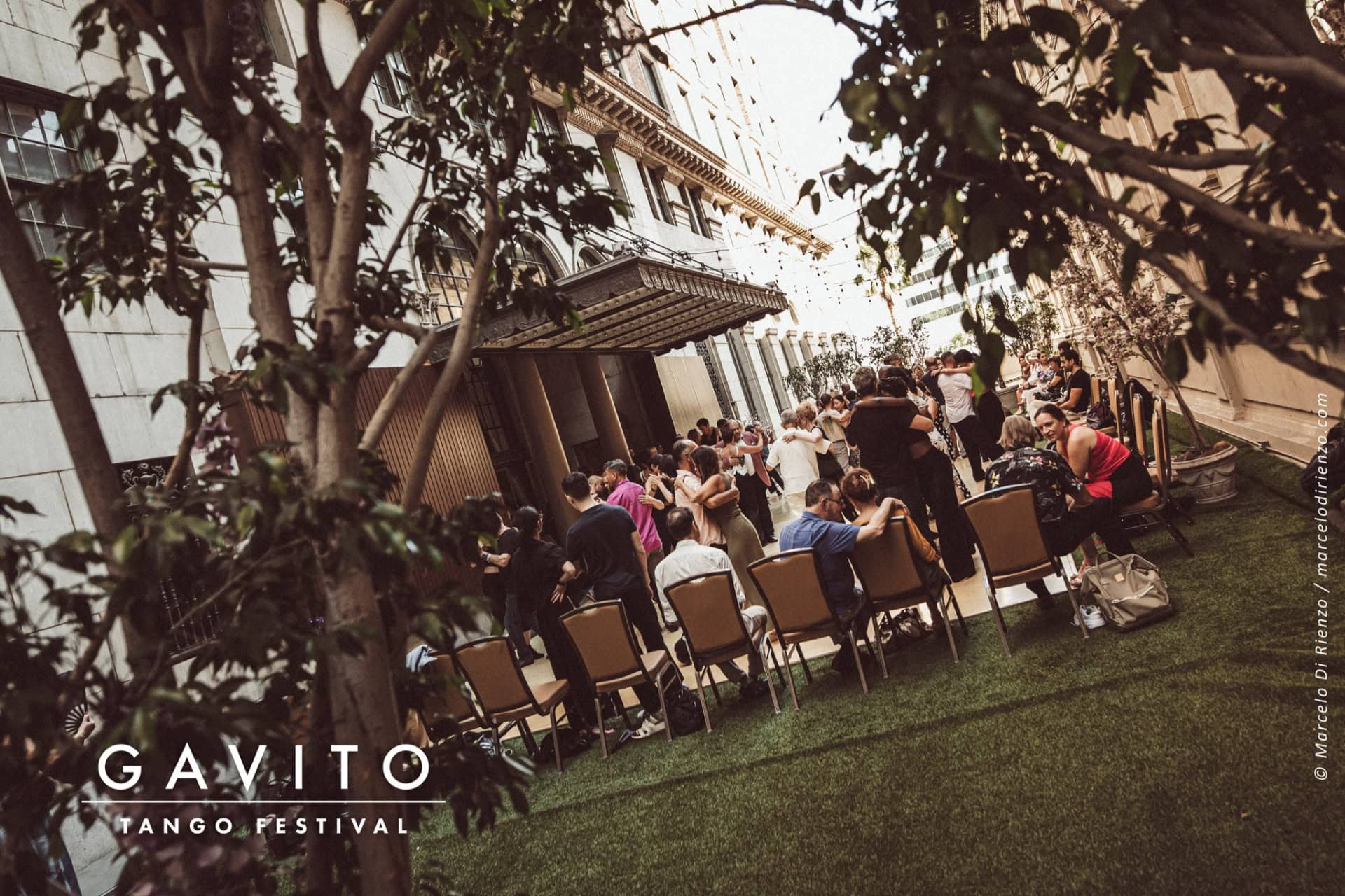 A lively outdoor gathering with people and festive decorations beside a gazebo.