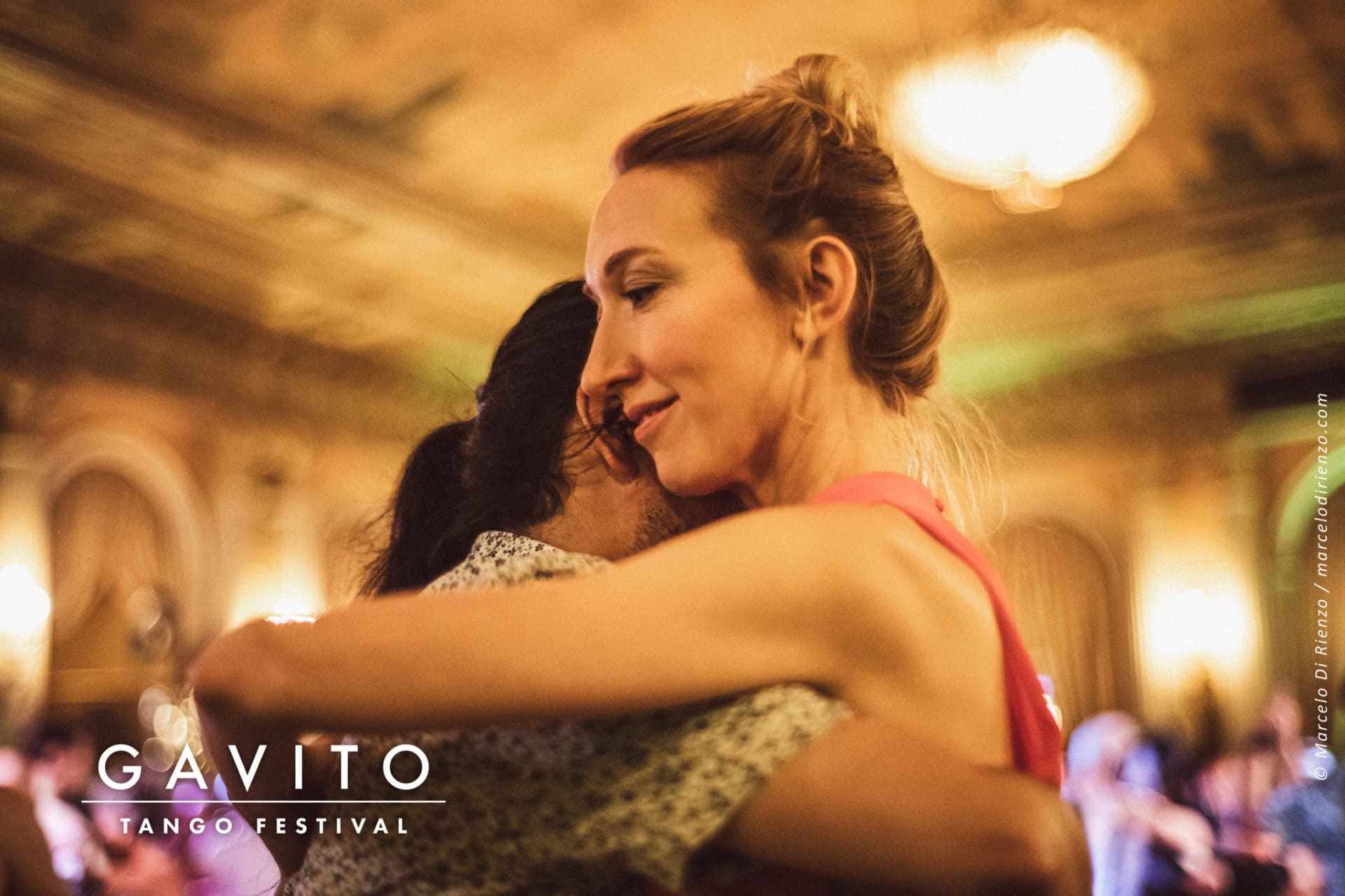 Two women embrace warmly in a softly lit room.