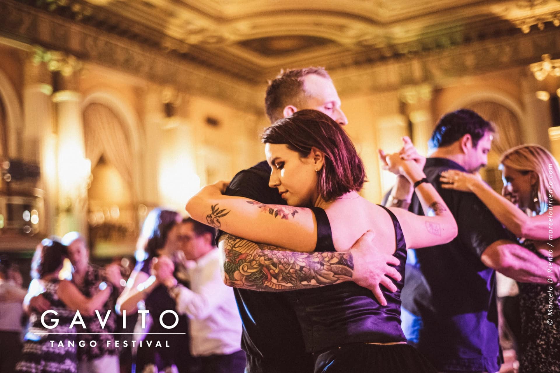 Couple dancing closely at a lively event in an elegant venue.