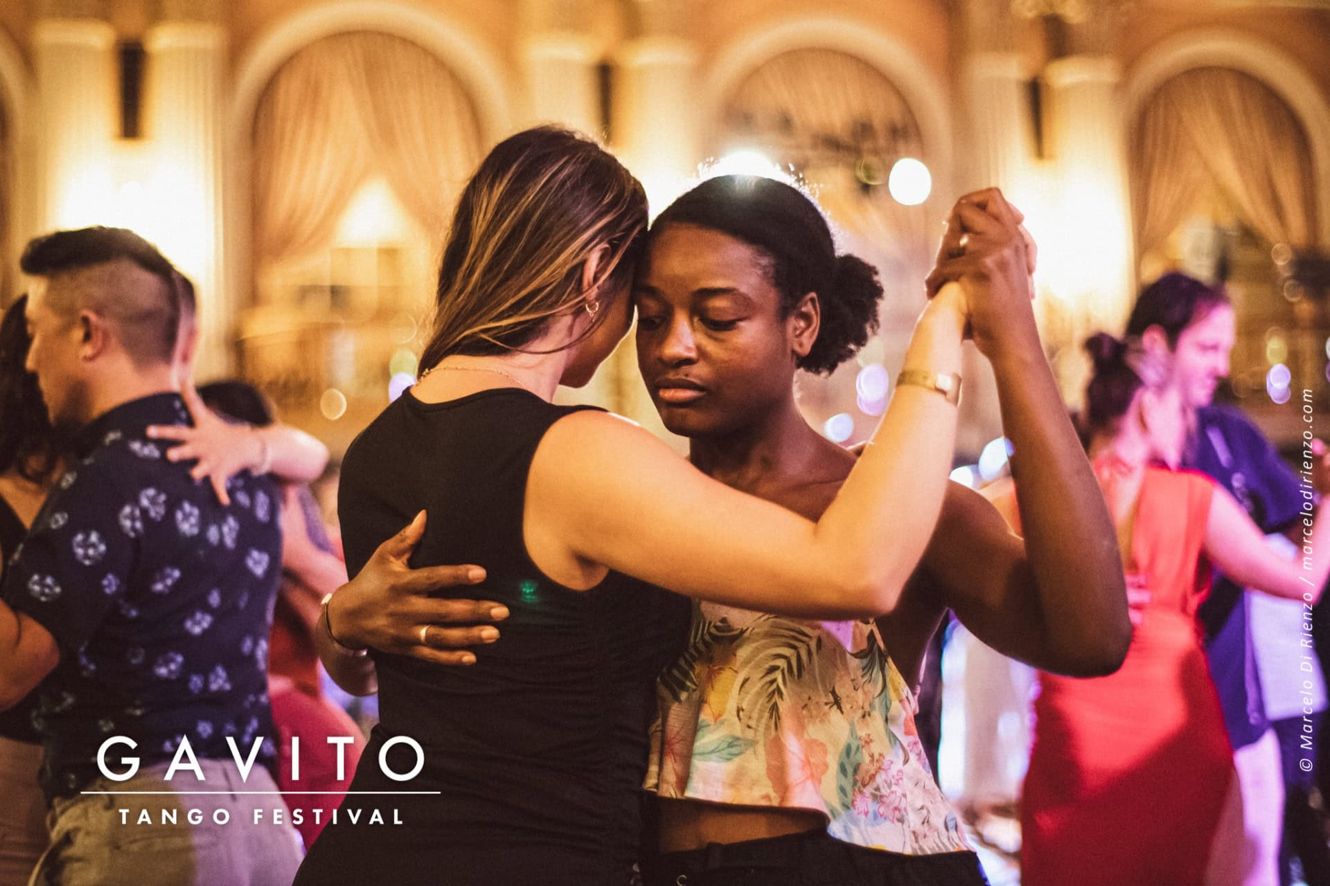 A couple dancing closely in an elegant ballroom setting.