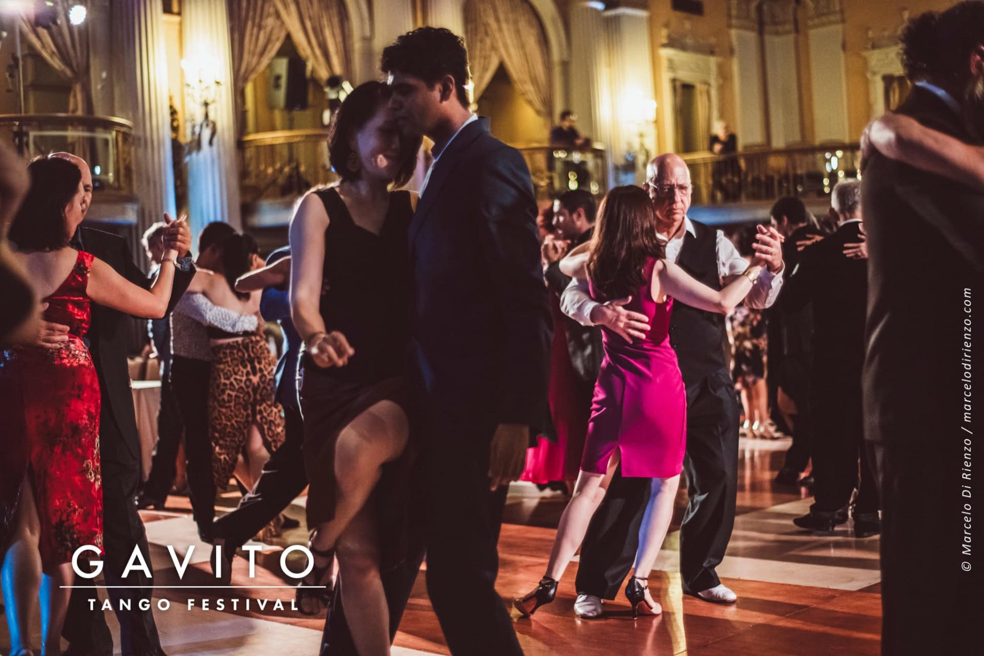 Couple dancing elegantly in a warmly lit ballroom.