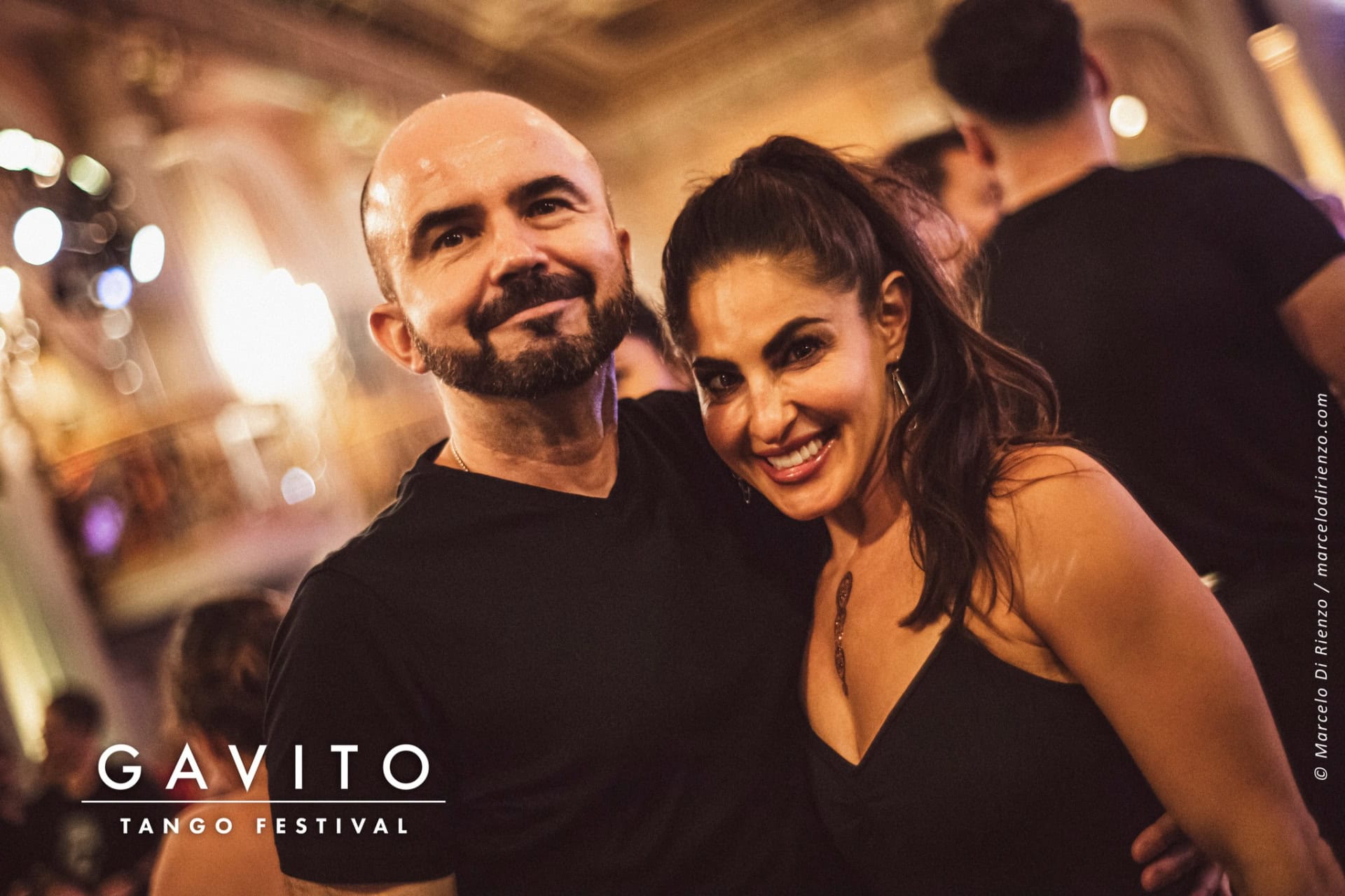 A smiling couple posing closely together at a social event.