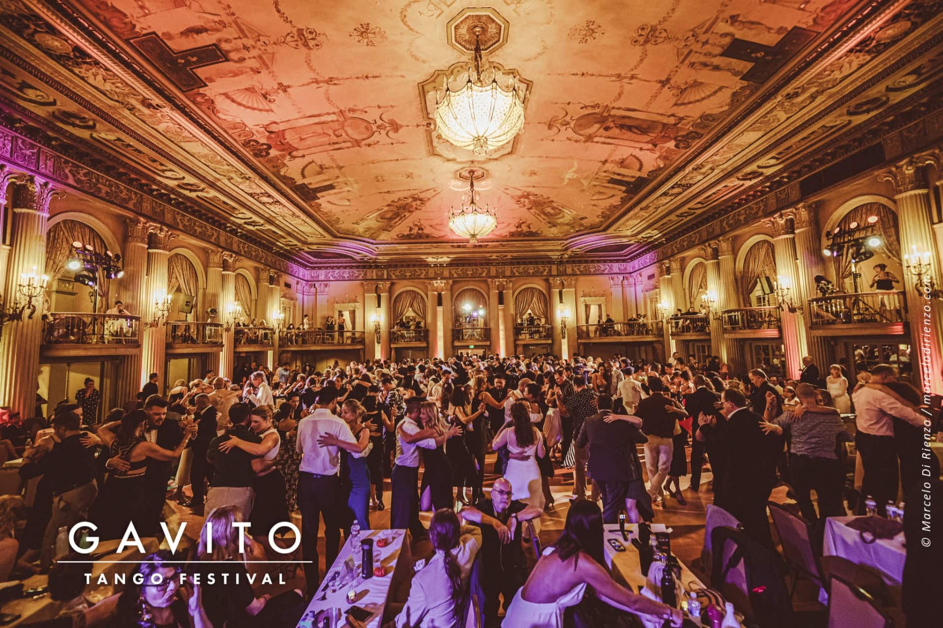 Elegant ballroom filled with guests and ornate decor.