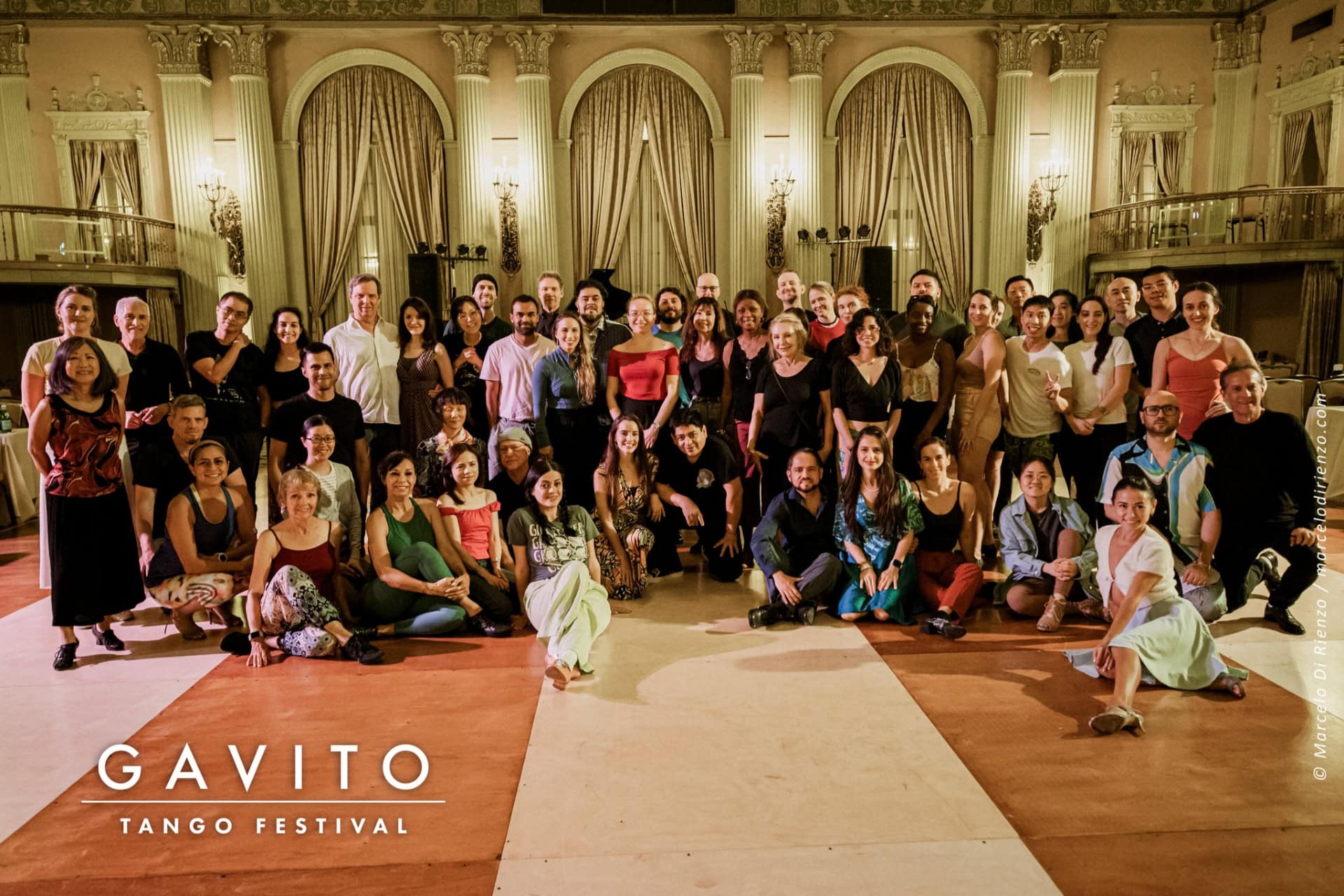 Large group photo in a grand hall with elegant decor.