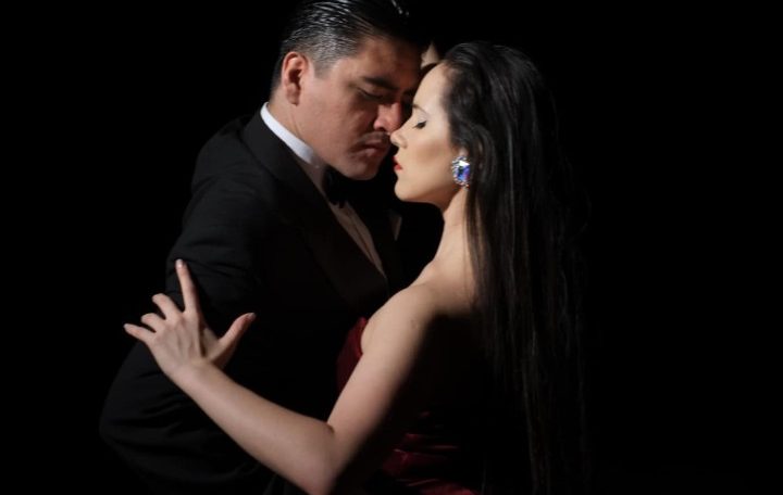 A couple embraces tenderly in a dark setting.