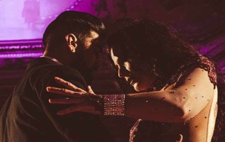 A romantic embrace between two people in a dimly lit setting.