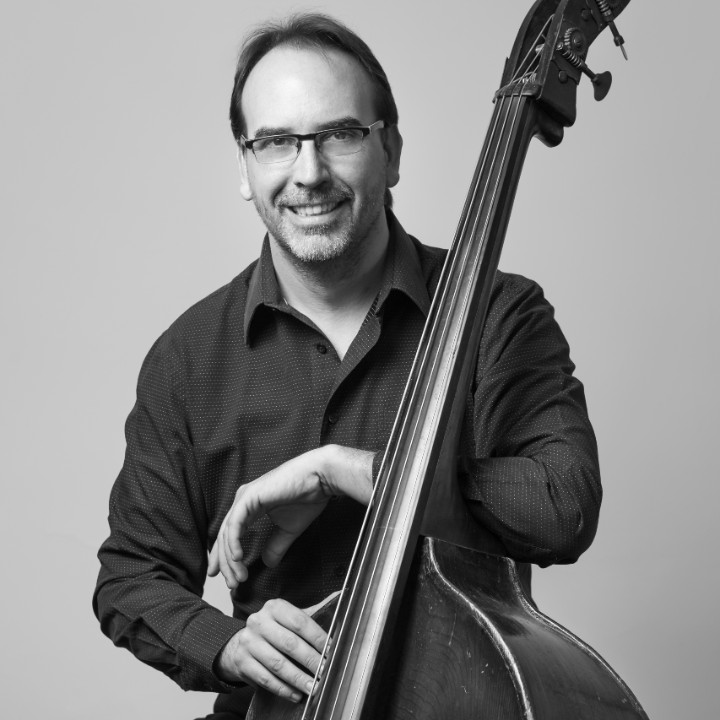 Man playing an upright bass with a bow in a studio.
