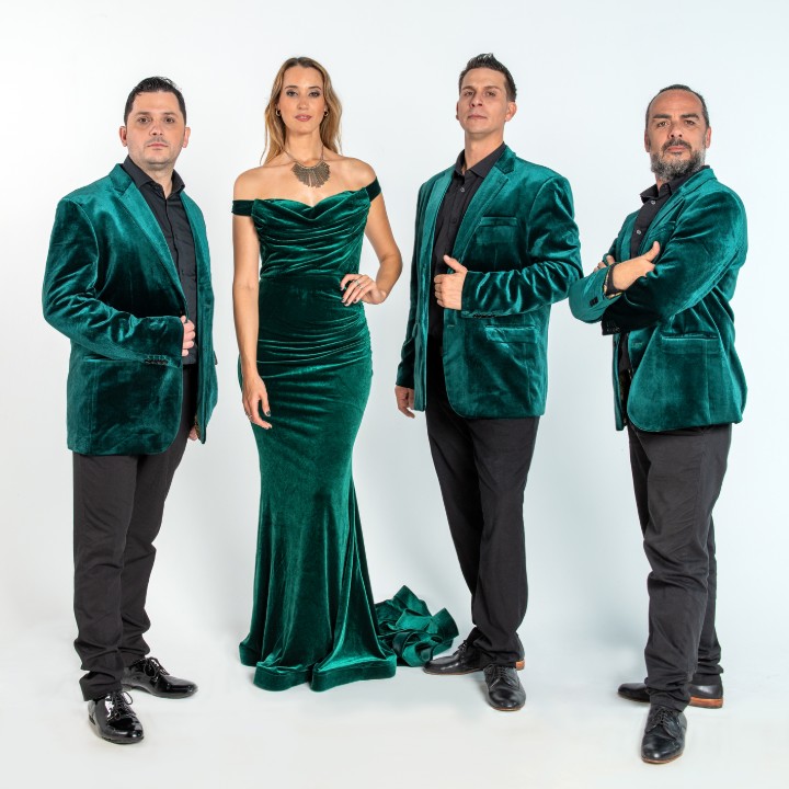 A group of four elegantly dressed people in green velvet outfits posing.