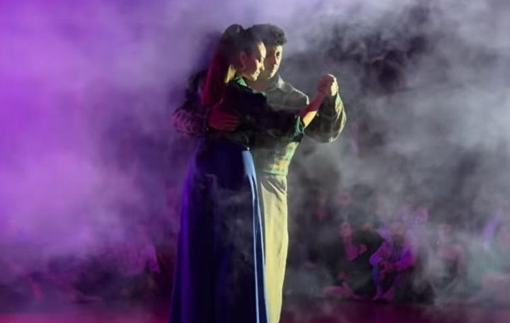 A performer singing passionately on stage with dramatic lighting and smoke effects.