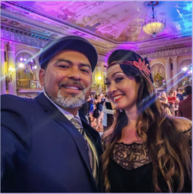 A smiling couple dressed elegantly at a festive event.